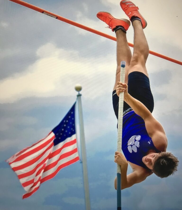 A pole vaulter clears the bar at an outdoor track competition