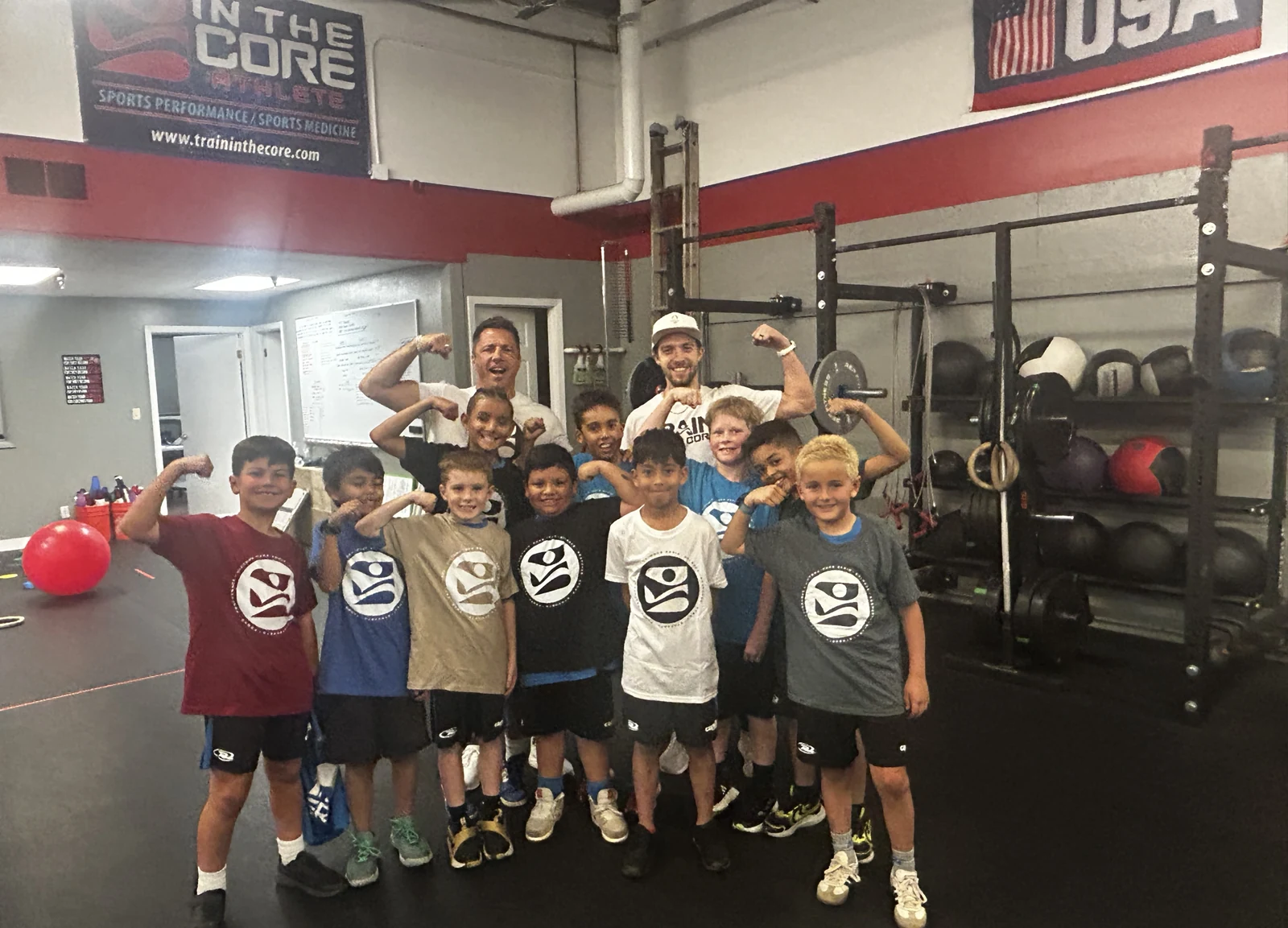 Rush Soccer Club youth athletes and their two In The Core Athlete coaches flexing together after a training session at the Boulder facility